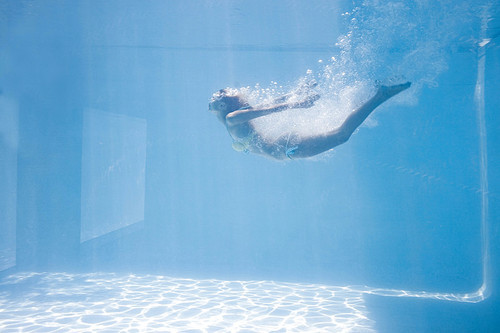 Fit woman swimming under water in the pool