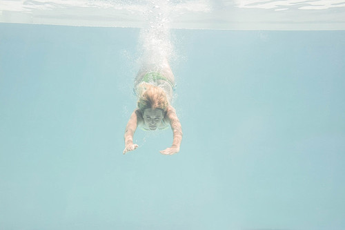 Fit woman swimming under water in the pool