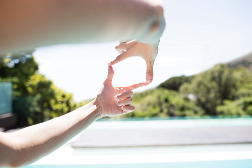 Woman making square with hands poolside