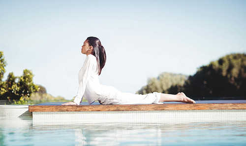 Calm brunette doing yoga by the pool