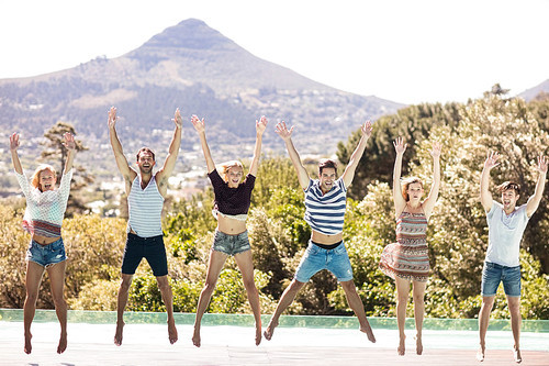 Happy friends jumping poolside