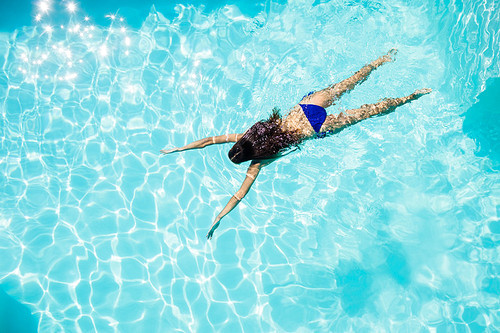 Calm woman floating in the pool in a sunny day