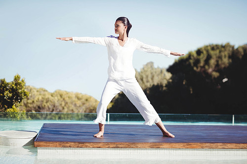 Calm brunette doing yoga by the pool