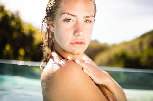 Unsmiling blonde in the pool crossing arms and looking at the camera