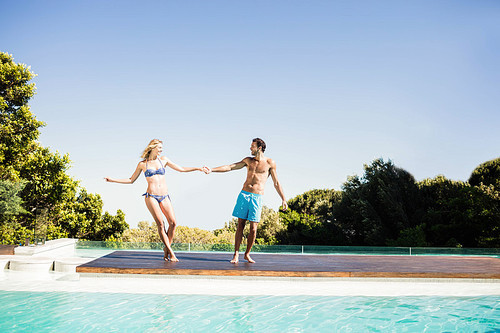 Cute couple holding hands by the pool