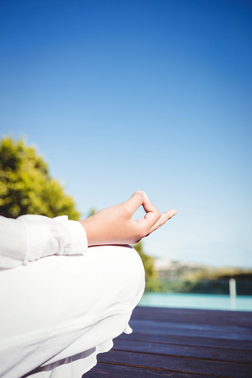 Calm brunette doing yoga by the pool