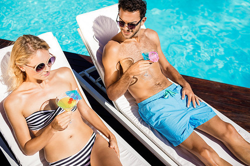 Couple relaxing on deckchairs by the pool