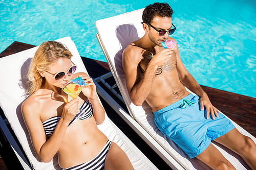 Couple relaxing on deckchairs by the pool