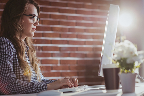 Focused hipster businesswoman watching computer at her desk in office