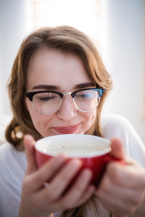 Pretty woman relaxing on couch with coffee in the living room