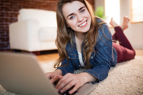 Pretty woman lying on the couch using laptop in the living room