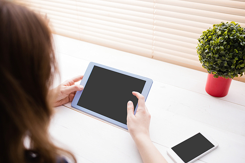 Hipster businesswoman using her tablet at her desk in office