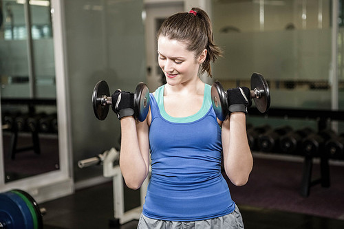 Fit woman lifting dumbbells at the gym