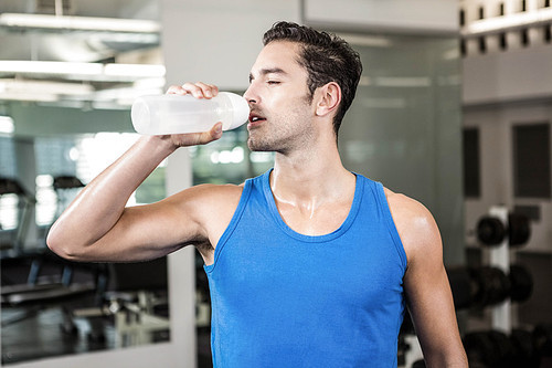 handsome man drinking water in the gym