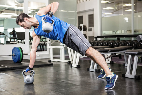 Muscular man doing exercises with kettlebells at the gym