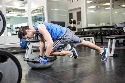 Muscular man exercising with bosu ball in the gym