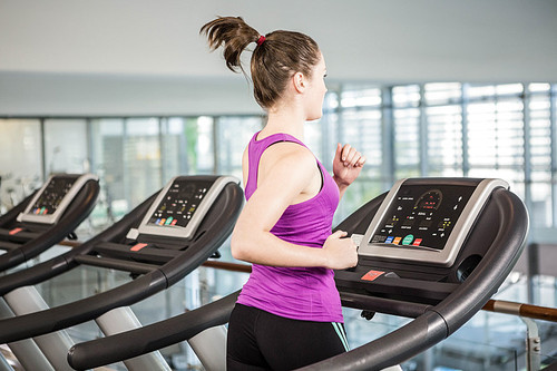 Fit woman running on treadmill in the gym