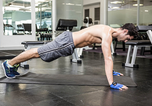 Shirtless man doing push up at the gym