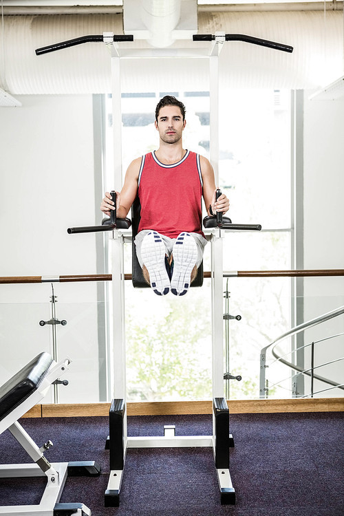 Muscular man doing pull up in a gym