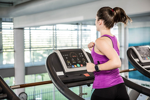 Fit brunette running on treadmill in the gym