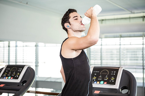 handsome man on treadmill drinking water at the gym