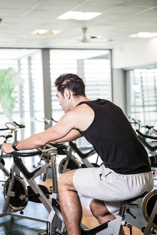 Focused man using exercise bike at the gym