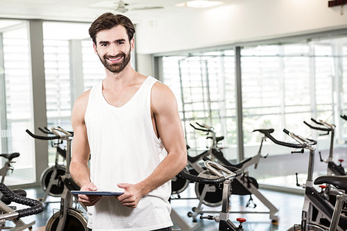 Smiling man holding tablet at the gym