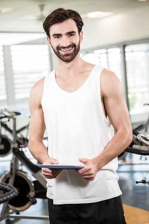 Smiling man holding tablet in the gym
