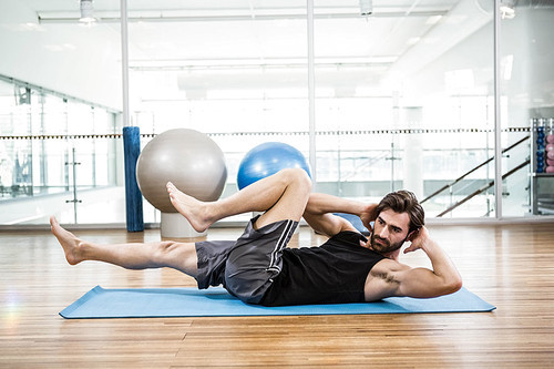 Muscular man doing abdominal on mat in the studio