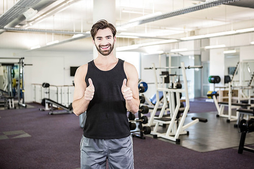 Smiling man showing thumbs up at the gym