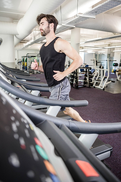 Handsome man running on treadmill at the gym