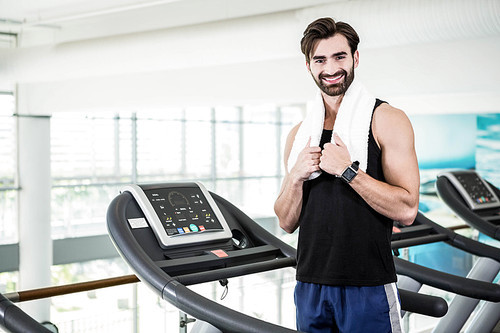 Smiling man standing on treadmill at the gym