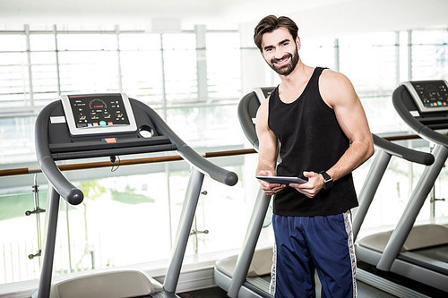 Smiling man using tablet at the gym