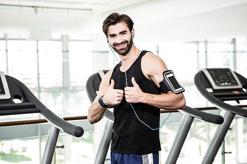 Smiling man showing thumbs up in the gym