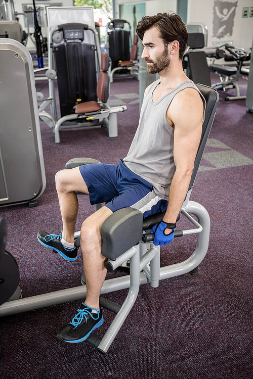 Focused man using weights machine for legs at the gym