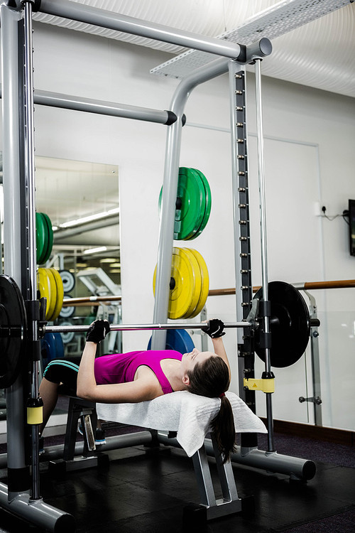 Fit woman lifting the barbell bench press in gym