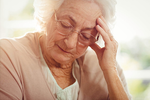 Elderly woman with headache at home