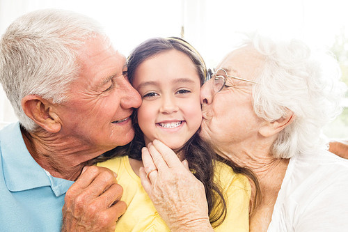 Grandparents kissing their granddaughter at home
