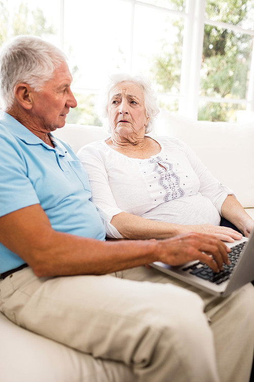 Focused senior couple using laptop at home