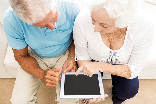 Focused senior couple using tablet at home