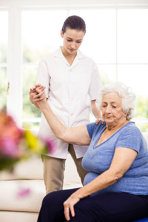 Physiotherapist taking care of sick elderly patient at home