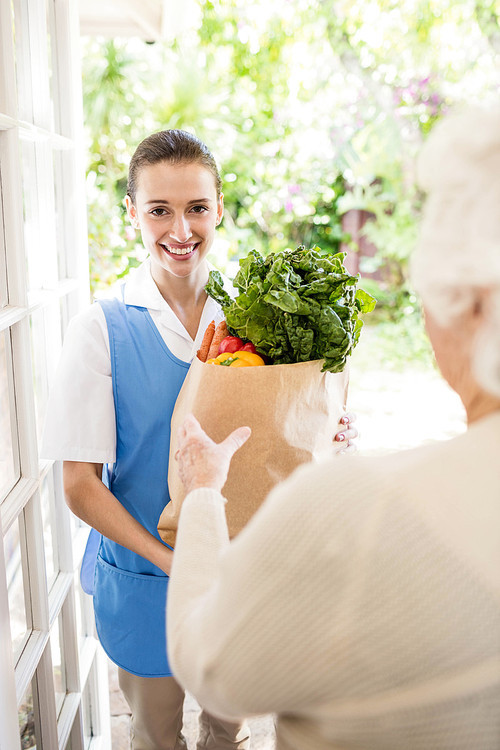 Nice nurse bringing vegetables to old patient at home