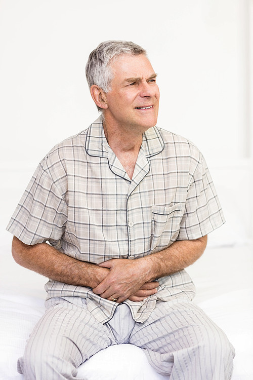 Suffering senior man holding his belly at home