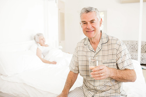 Peaceful senior man holding glass of water at home