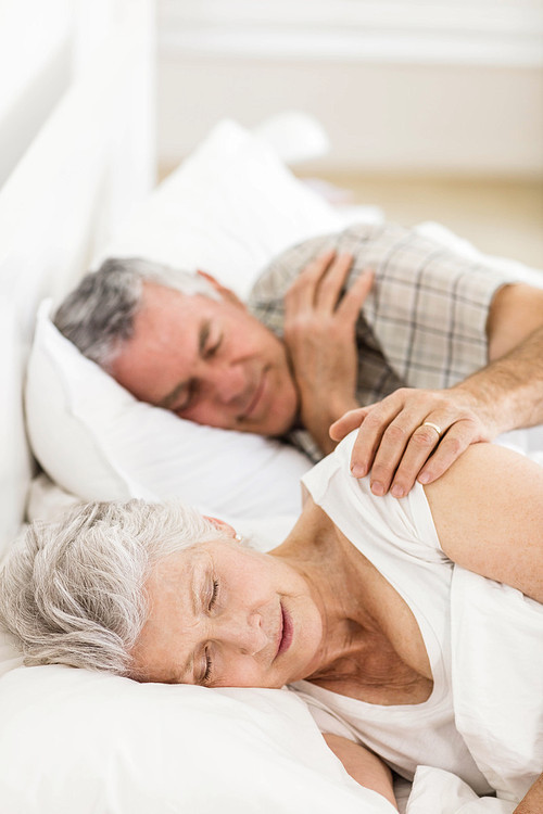 Senior couple sleeping in bed at home