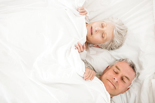 Senior couple sleeping in bed under blanket