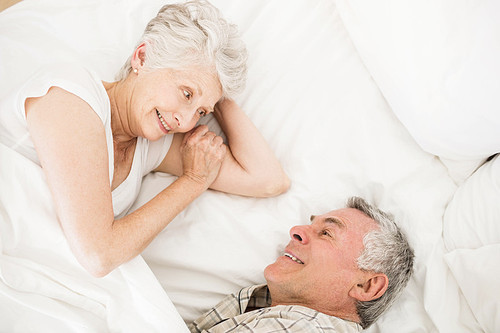 Happy senior couple on bed talking