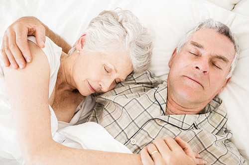 Peaceful senior couple sleeping on bed
