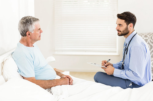 Handsome nurse visiting a mature man in bedroom