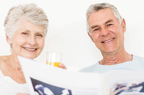 Senior couple reading newspaper at bed